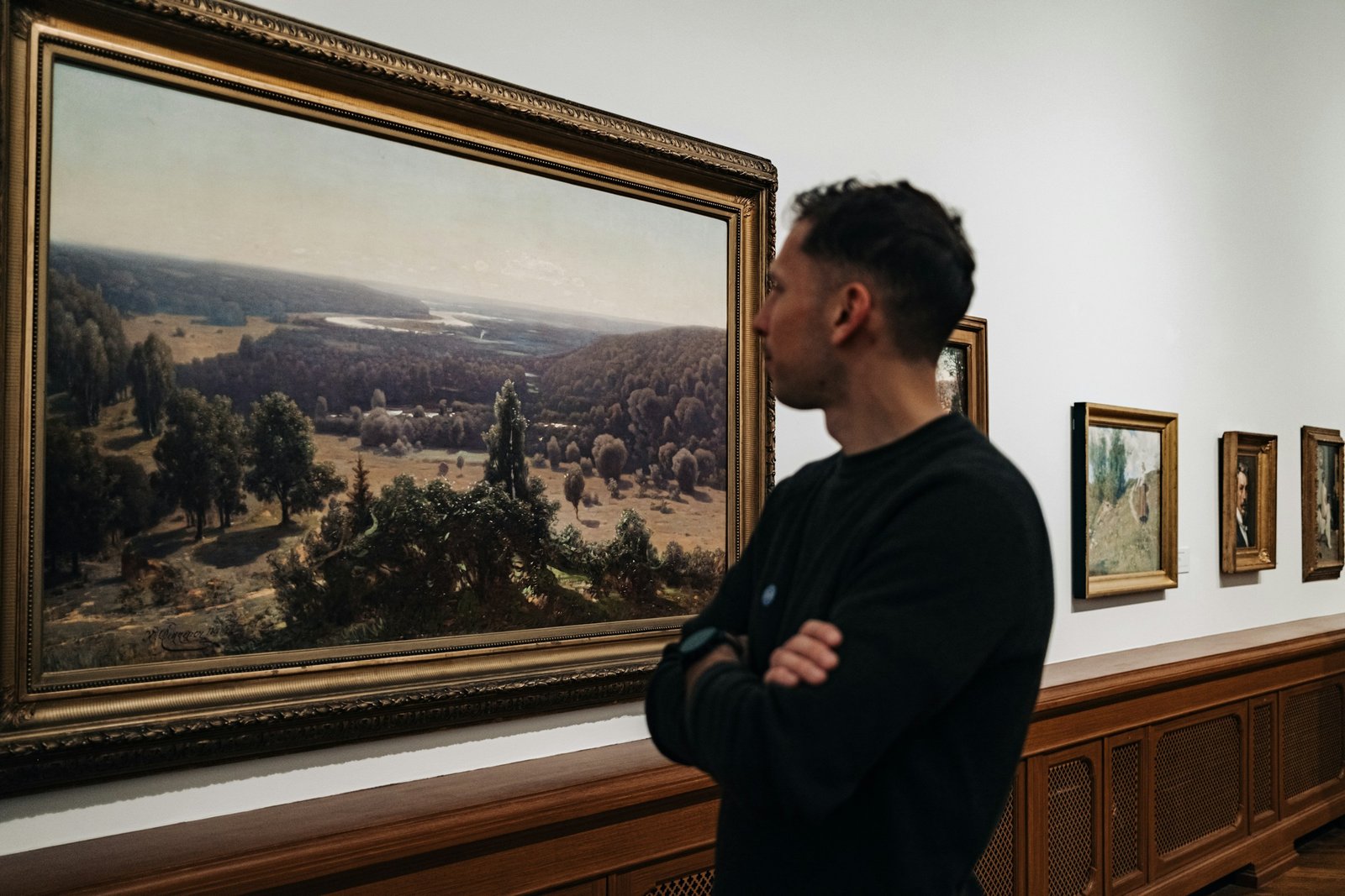 A collector contemplating a framed painting in an art gallery